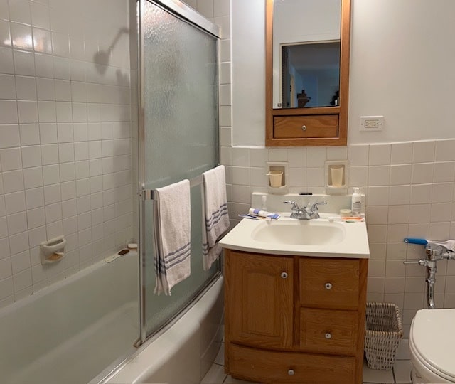 full bathroom featuring enclosed tub / shower combo, vanity, tile patterned floors, tile walls, and toilet