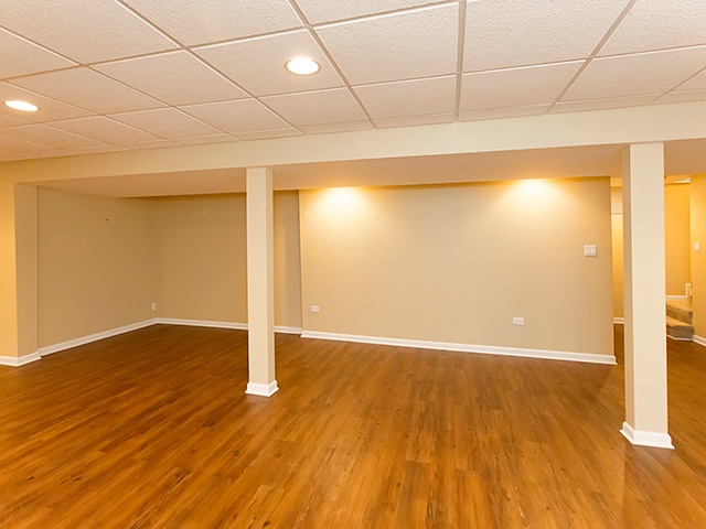 basement featuring a paneled ceiling and wood-type flooring