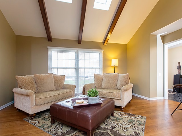 living room featuring beamed ceiling, hardwood / wood-style floors, high vaulted ceiling, and a skylight