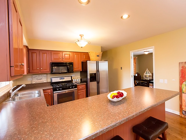 kitchen featuring kitchen peninsula, stainless steel appliances, hardwood / wood-style floors, sink, and a kitchen bar