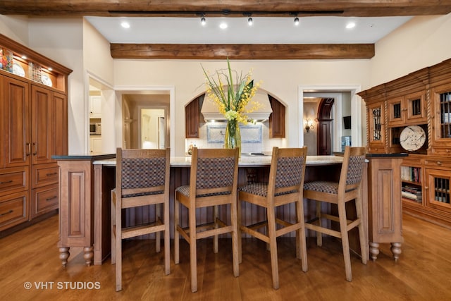 dining space with wood-type flooring and beam ceiling