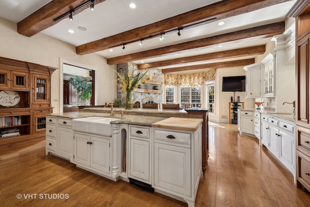 kitchen featuring white cabinetry, beamed ceiling, and light wood-type flooring