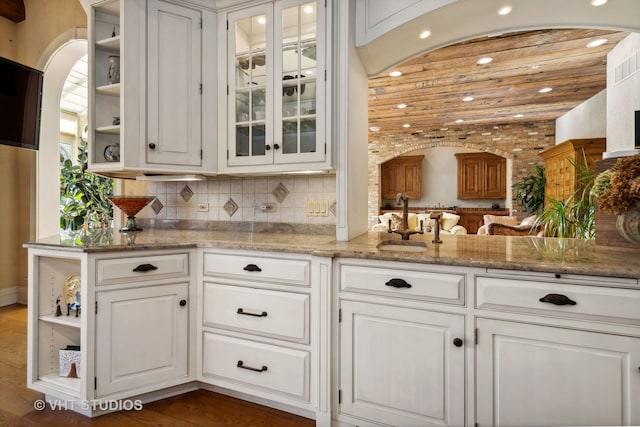 bar with white cabinetry, sink, light stone countertops, and dark hardwood / wood-style floors