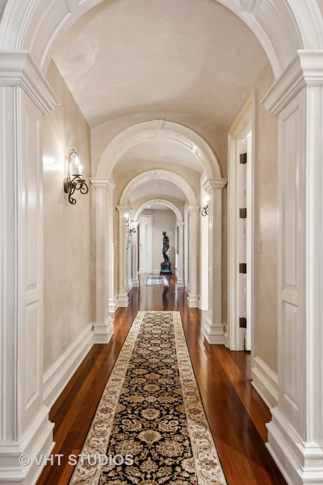 hall with ornate columns and dark wood-type flooring