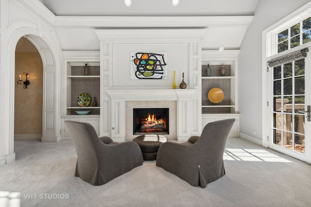 living room with built in shelves, a fireplace, lofted ceiling, and light carpet