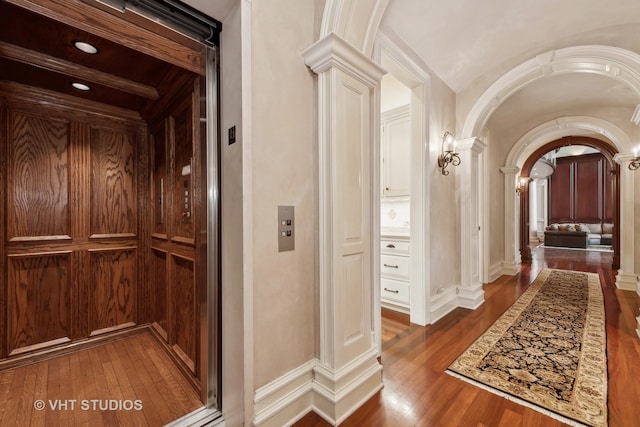 corridor featuring dark hardwood / wood-style floors, elevator, and decorative columns