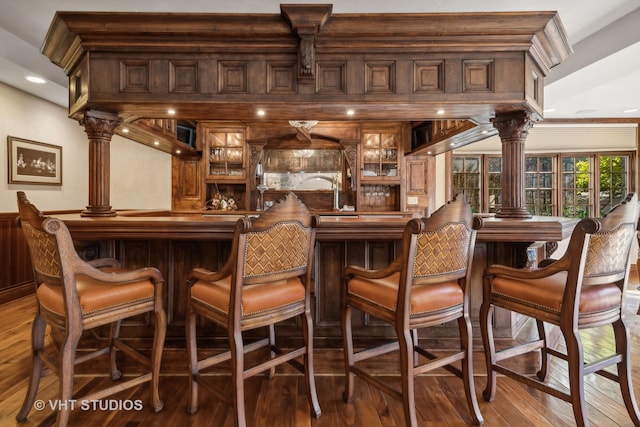 bar featuring ornate columns and wood-type flooring