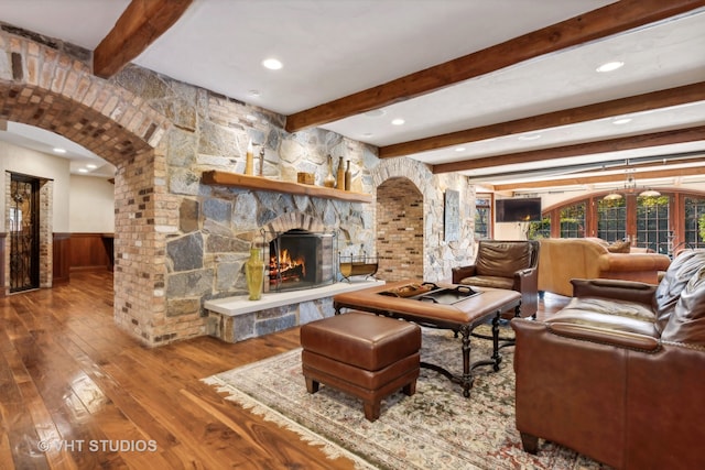 living room featuring hardwood / wood-style flooring, beam ceiling, a fireplace, and french doors