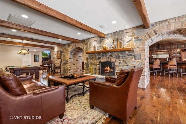 living room with a stone fireplace, hardwood / wood-style floors, beamed ceiling, and pool table