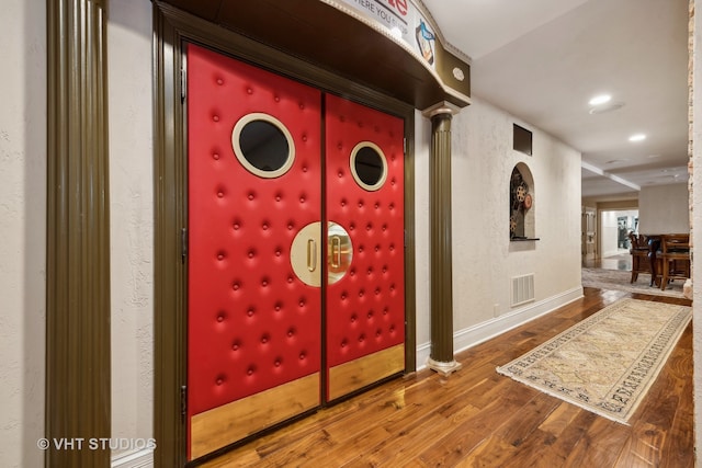 interior space featuring hardwood / wood-style flooring and ornate columns