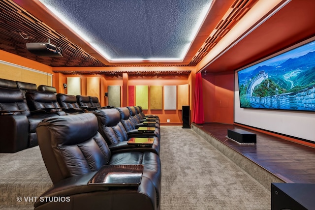 home theater room with a textured ceiling, carpet floors, and a tray ceiling