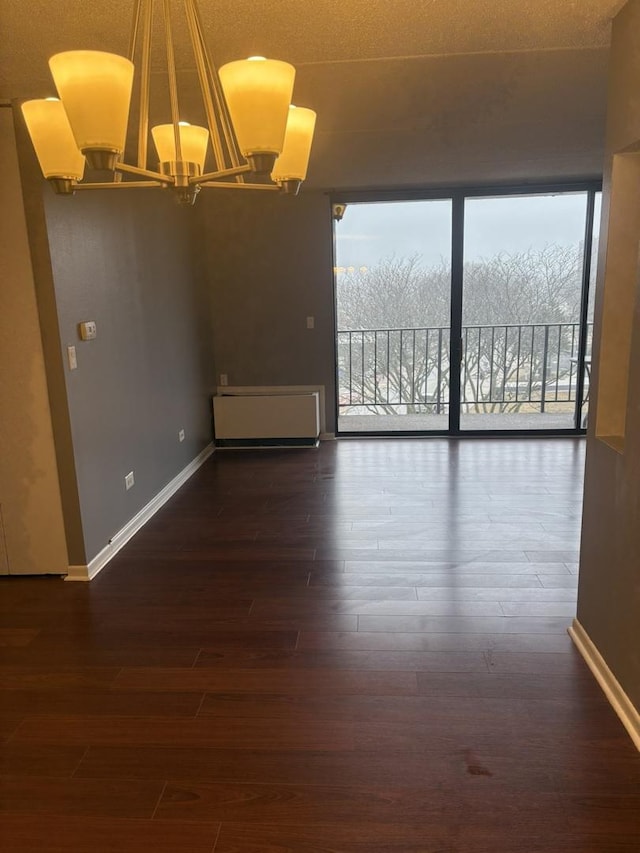 empty room featuring an inviting chandelier, plenty of natural light, and dark hardwood / wood-style flooring