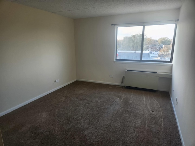 empty room with a textured ceiling and dark colored carpet