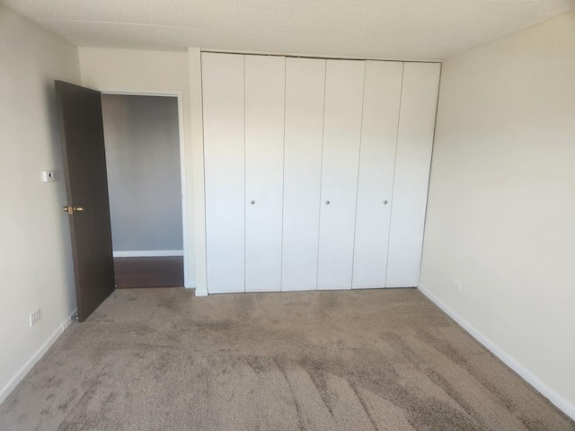 unfurnished bedroom with light colored carpet and a closet