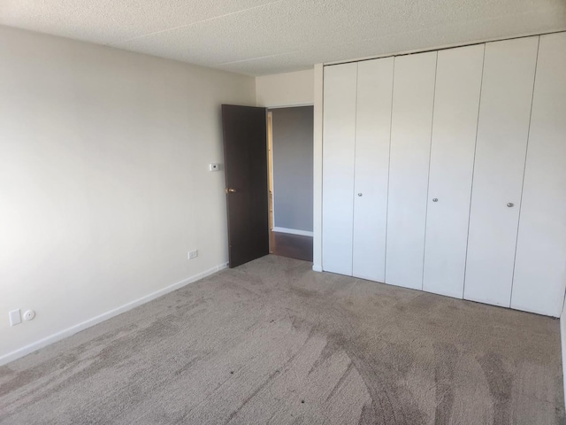 unfurnished bedroom with light carpet, a closet, and a textured ceiling