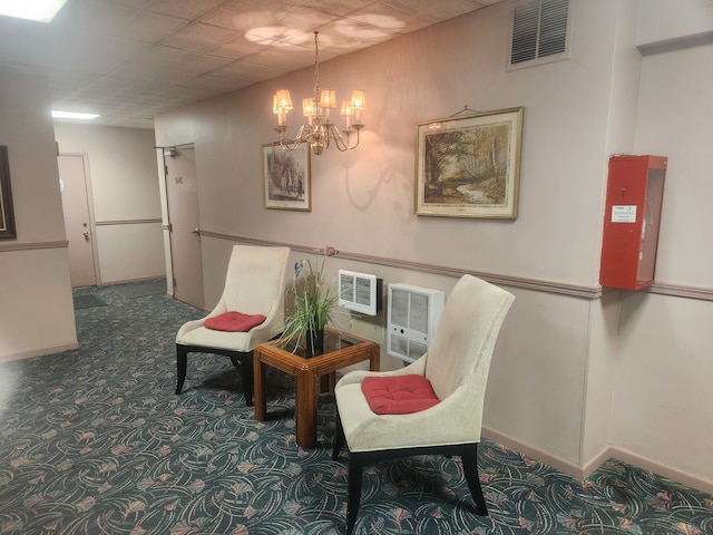 sitting room featuring a paneled ceiling, carpet flooring, a chandelier, and heating unit