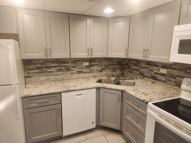 kitchen with tasteful backsplash, white appliances, gray cabinets, and sink