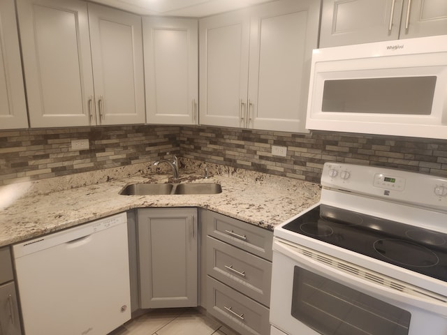 kitchen featuring sink, gray cabinetry, backsplash, and white appliances