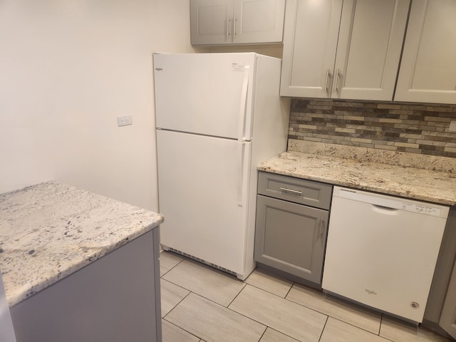 kitchen with gray cabinetry, backsplash, white appliances, and light stone countertops