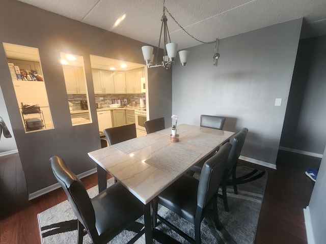 dining space featuring dark wood-type flooring, an inviting chandelier, and a textured ceiling