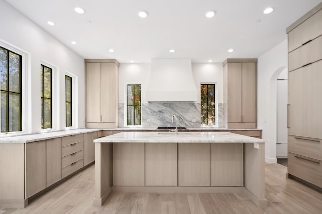 kitchen with custom exhaust hood, light brown cabinets, and light wood-type flooring