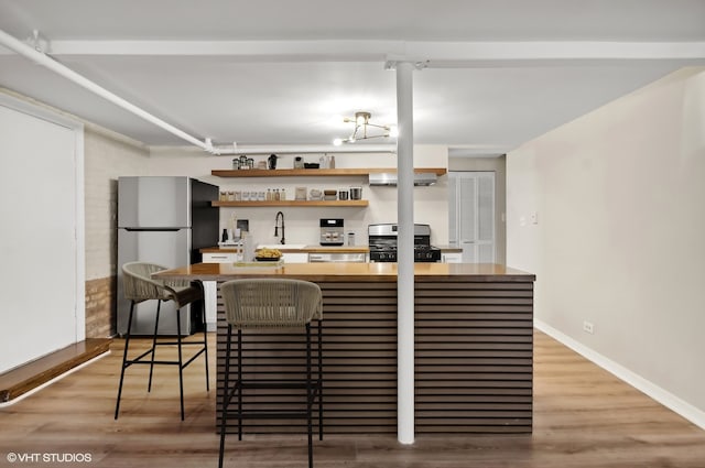 kitchen with hardwood / wood-style floors, a breakfast bar area, sink, and appliances with stainless steel finishes