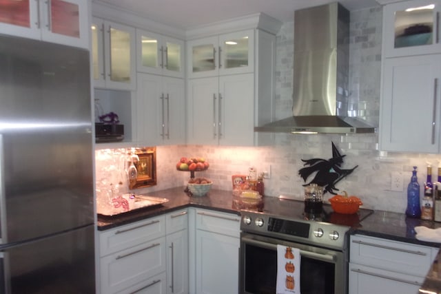 kitchen featuring wall chimney range hood, appliances with stainless steel finishes, and white cabinets