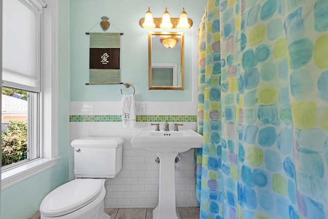 bathroom featuring walk in shower, sink, tile walls, tile patterned flooring, and toilet