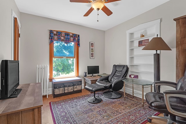 living area with wood-type flooring, ceiling fan, and radiator