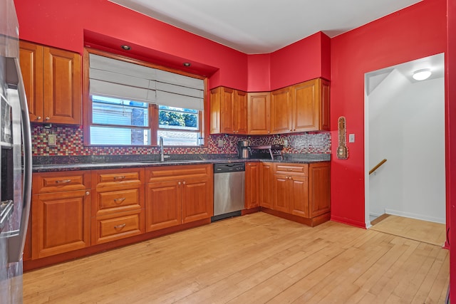 kitchen featuring appliances with stainless steel finishes, light wood-type flooring, decorative backsplash, and sink