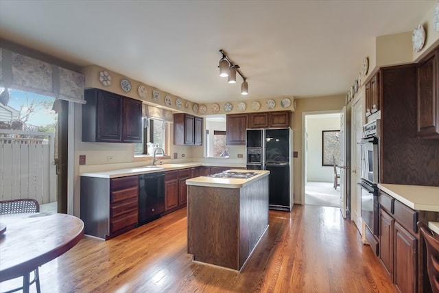 kitchen featuring plenty of natural light, a kitchen island, black appliances, and light wood-type flooring