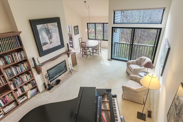 carpeted living room with a tiled fireplace, high vaulted ceiling, and an inviting chandelier