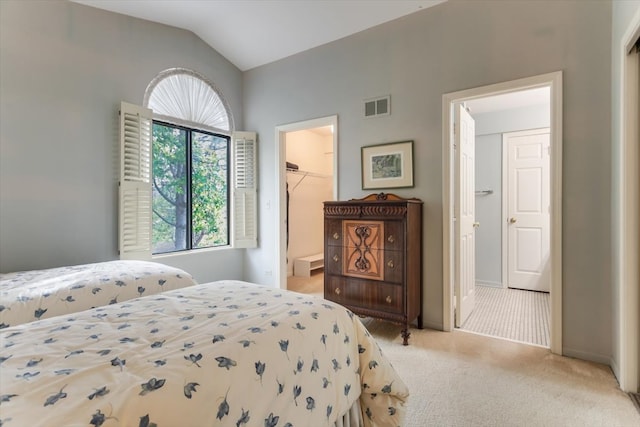 carpeted bedroom with a walk in closet, vaulted ceiling, a closet, and connected bathroom