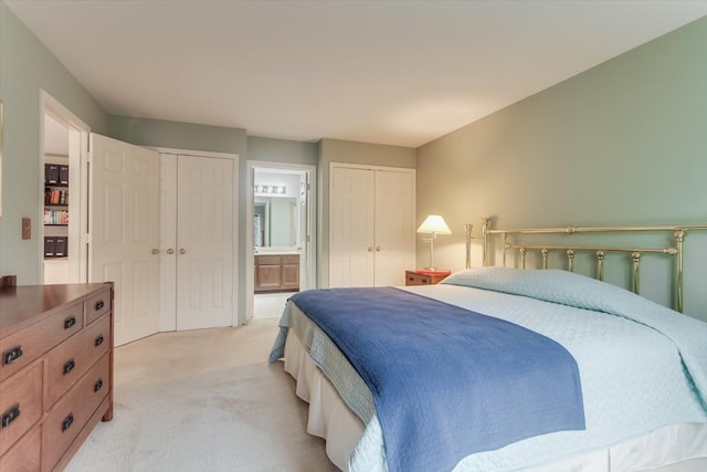 carpeted bedroom with ensuite bathroom and two closets