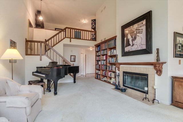 sitting room with carpet, a towering ceiling, and a tile fireplace