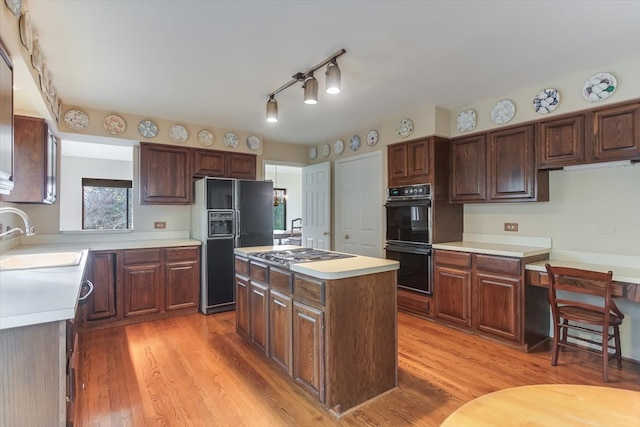 kitchen featuring sink, a kitchen island, black appliances, and light hardwood / wood-style floors