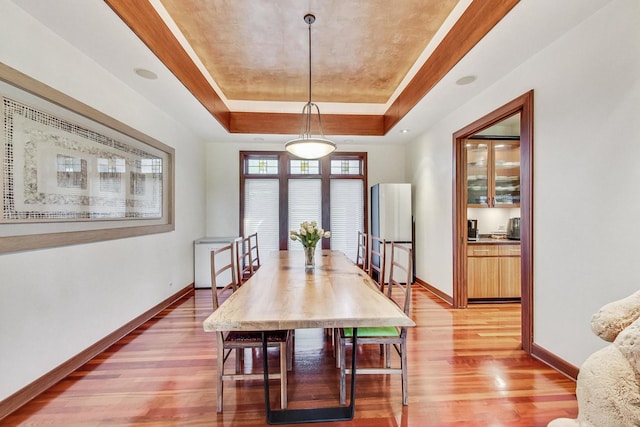 dining space featuring a tray ceiling and hardwood / wood-style flooring