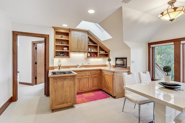 kitchen featuring kitchen peninsula, light carpet, sink, and a skylight