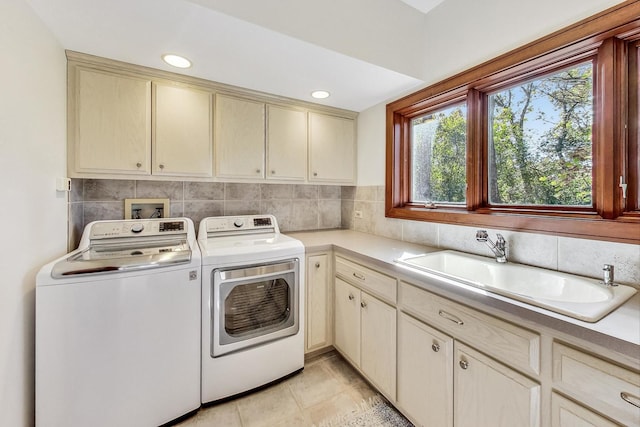 laundry room featuring cabinets, light tile patterned floors, sink, and washing machine and clothes dryer