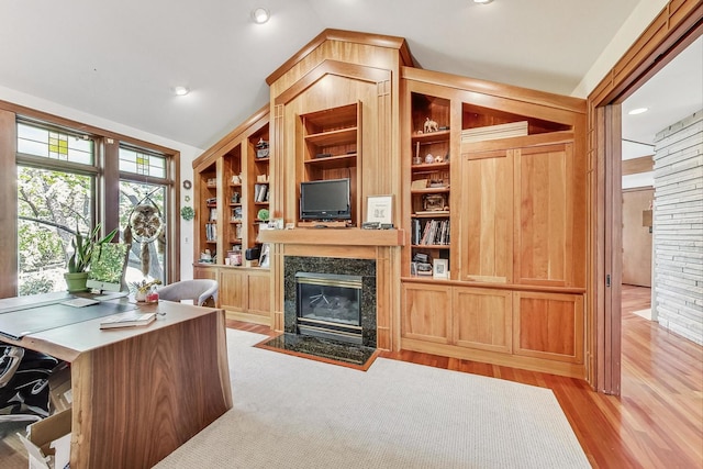 home office featuring vaulted ceiling, light hardwood / wood-style flooring, and a premium fireplace