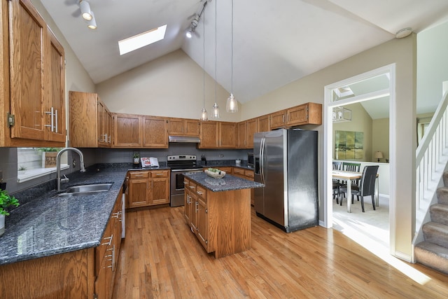 kitchen with stainless steel appliances, sink, a center island, light wood-type flooring, and rail lighting