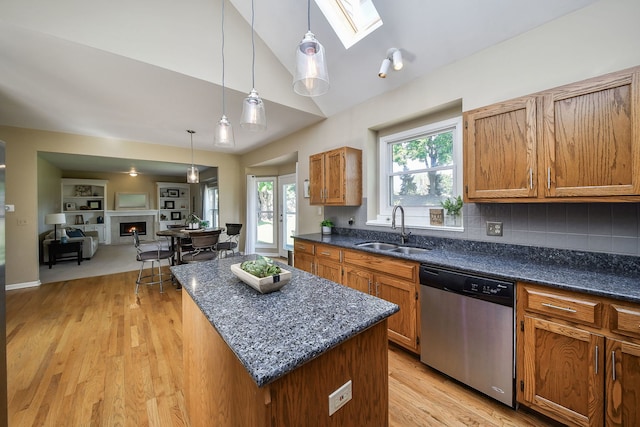 kitchen with dishwasher, sink, vaulted ceiling with skylight, decorative light fixtures, and a center island