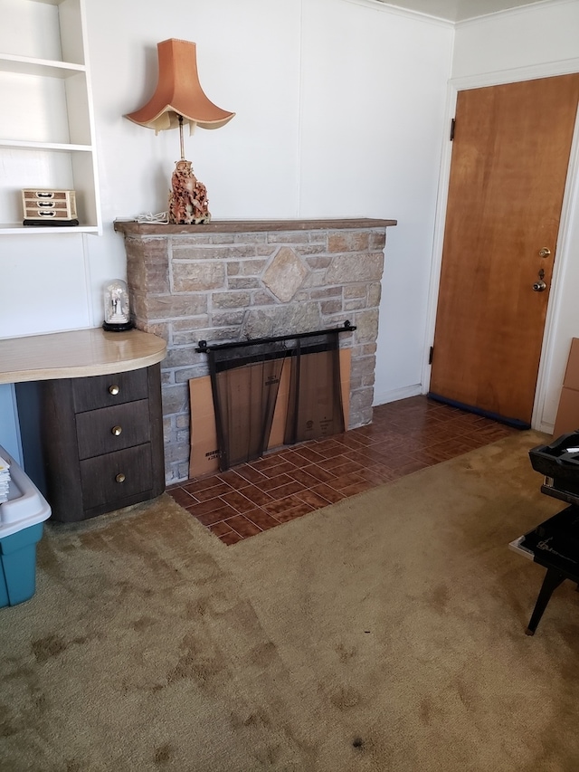 unfurnished living room with ornamental molding, dark colored carpet, and a stone fireplace