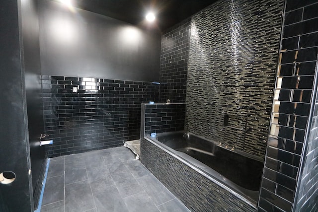 bathroom featuring a relaxing tiled tub, tile patterned flooring, and tile walls