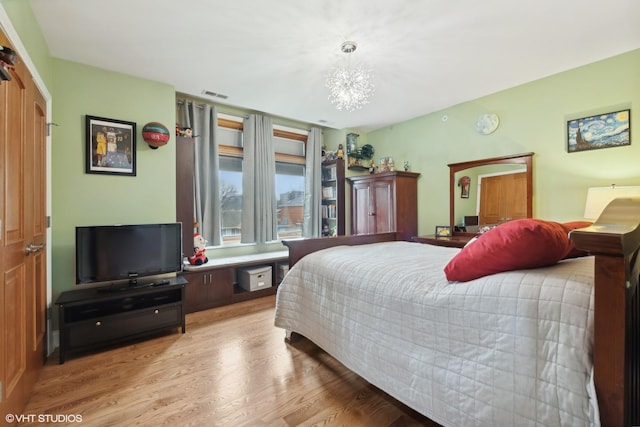 bedroom with light hardwood / wood-style floors and a notable chandelier