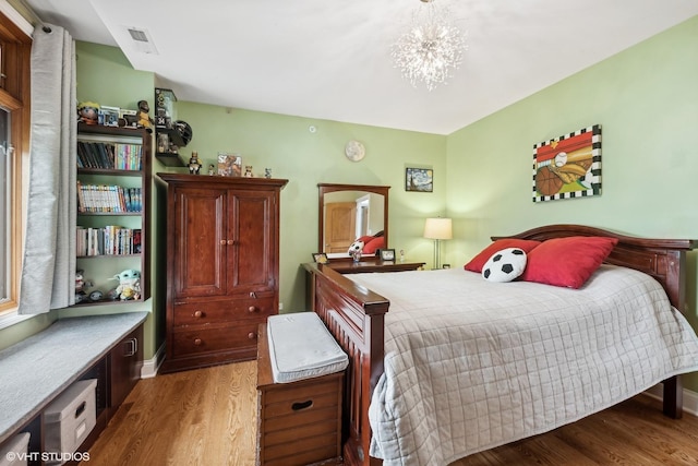 bedroom with hardwood / wood-style floors and an inviting chandelier