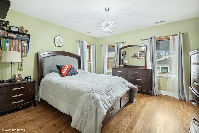 bedroom with a notable chandelier and light hardwood / wood-style floors