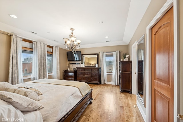 bedroom featuring light hardwood / wood-style floors, multiple windows, and a notable chandelier