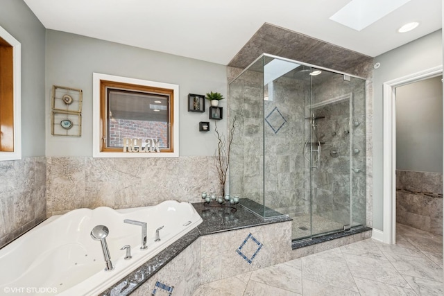 bathroom featuring plus walk in shower, a skylight, and tile patterned floors