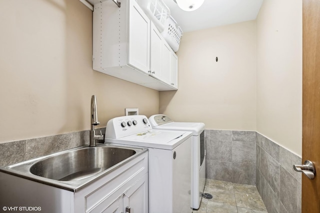 laundry area with cabinets, sink, washer and dryer, tile walls, and light tile patterned flooring